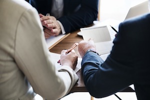 A couple seen from behind meeting with an attorney. Only their arms and hands are shown on either side of a desk.