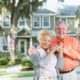 A senior couple standing in front of their home.