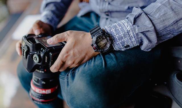 A man's hands hold a digital camera.