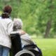 An older woman in a wheelchair with a younger person